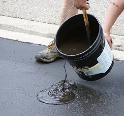 pouring asphalt sealer armor coat on driveway