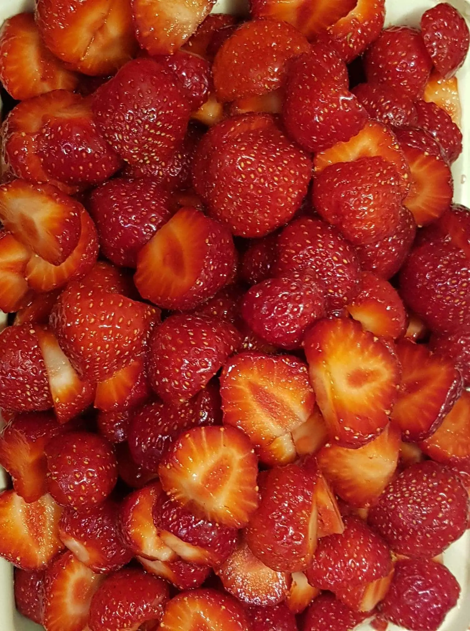 Sliced strawberries that are freshly picked and washed and packed for picnic foods.