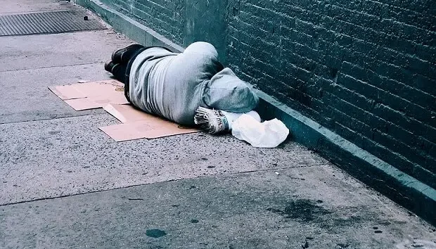 Financial difficulty homeless sleeping against a wall