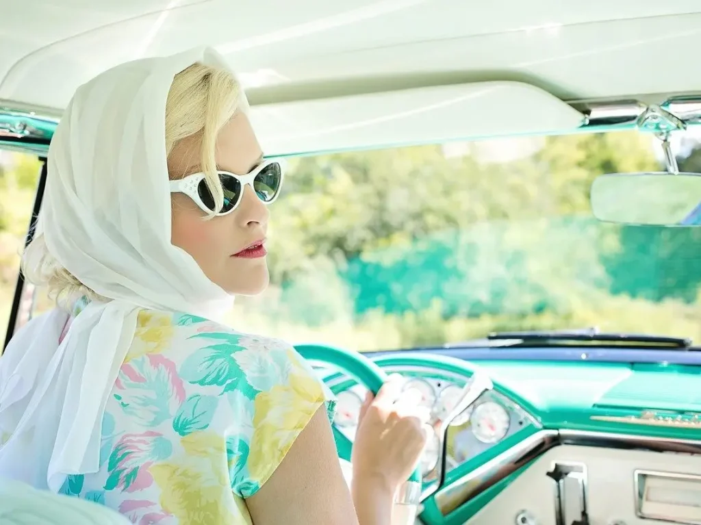 Vehicle expenses Income tax Blonde woman with white sunglasses in a vintage car.