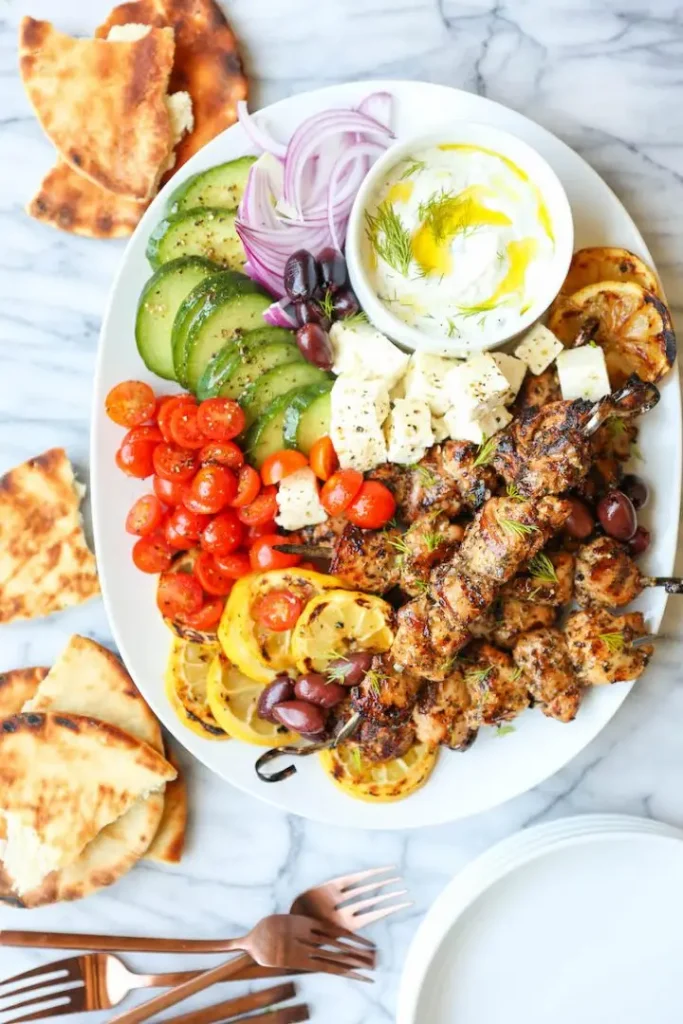 Greek Chicken Kabobs with a fresh side or sliced vegetables and lemon with side flatbread or pita bread. The perfect Father's Day 2021 dinner.