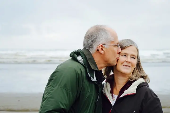 Senior couple at the beach standing in the sand.