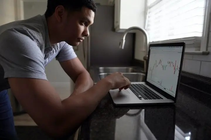 Reasons why you should invest. Man investing on a laptop at a desk.