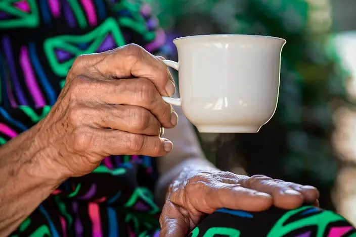 A senior enjoying a cuppa tea outside in the gardens.