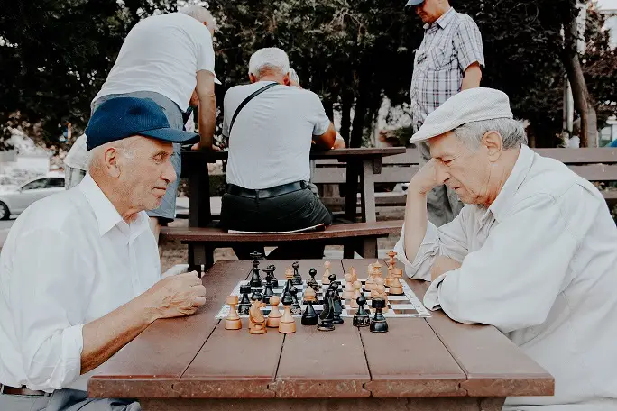 Two seniors enjoying a game of chess outside of their long-term care home