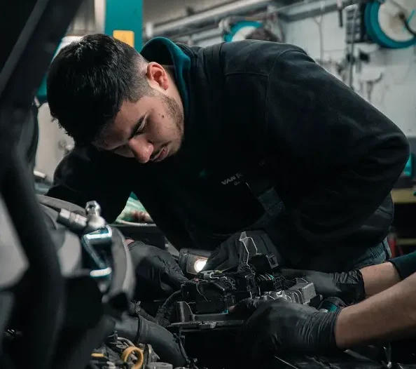 Two mechanics looking under the hood of a car to find what the problem is before the warranty runs out.