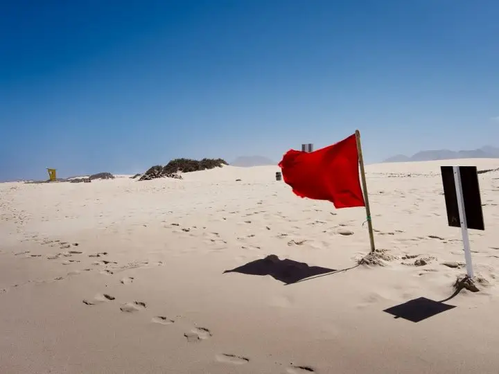 A red flag in the sand at the beach means caution