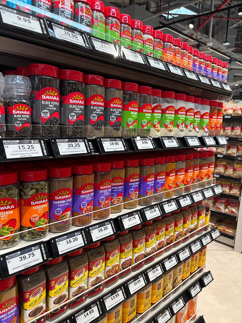 Authentic photograph of electronic shelf price labels beneath spice products in a supermarket in the United Arab Emirates.