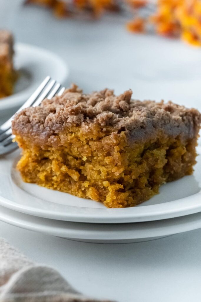 Slice of pumpkin coffee cake with crumb topping on a white plate