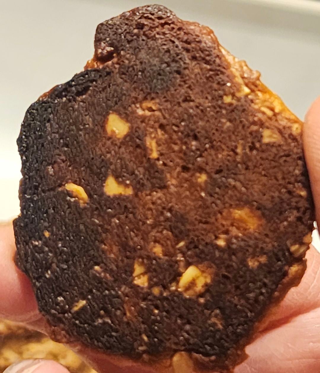 Very dark brown underside of a honey-sweetened peanut butter oatmeal cookie from the test batch