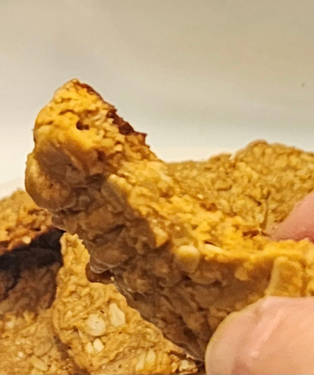 Broken-open peanut butter oatmeal cookie showing the rolled oats and dense texture inside